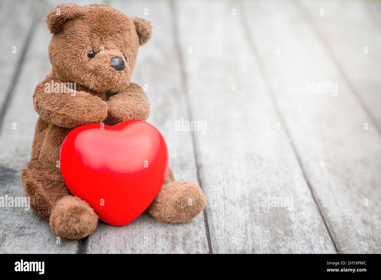 Oso Marrón y Corazón Rojo con el fondo de madera vieja para cuidar tu amor  Fotografía de stock - Alamy