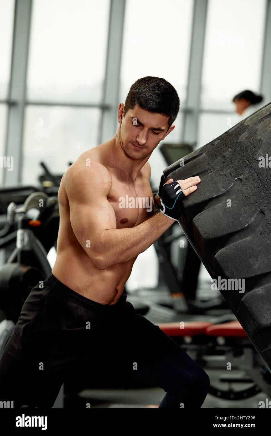 El hombre de la aptitud muscular volteando rueda del neumático. Concepto de  entrenamiento funcional gimnasio Fotografía de stock - Alamy