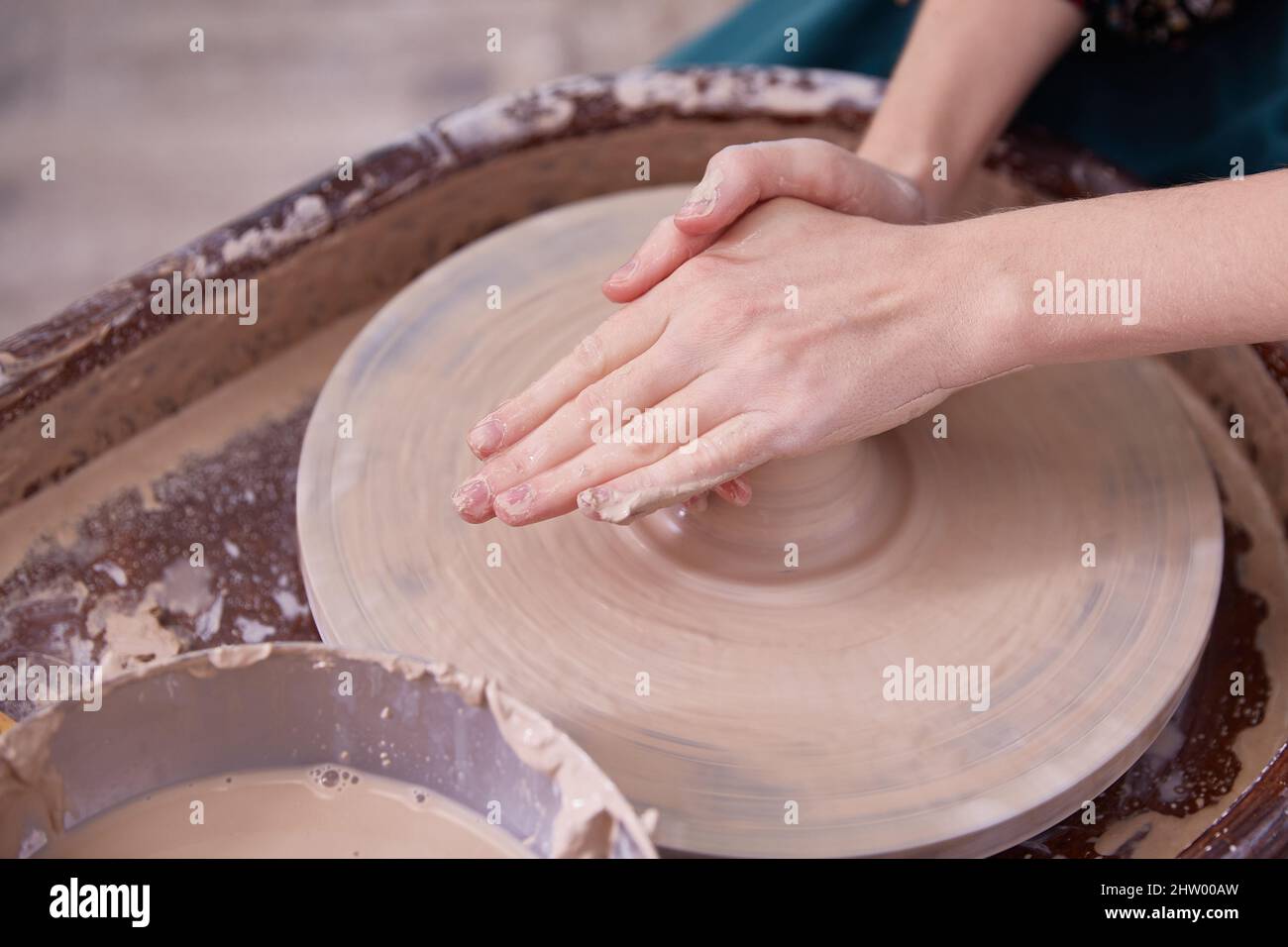 Las hermosas manos de las mujeres hacen platos de cerámica en la rueda de un alfarero Foto de stock