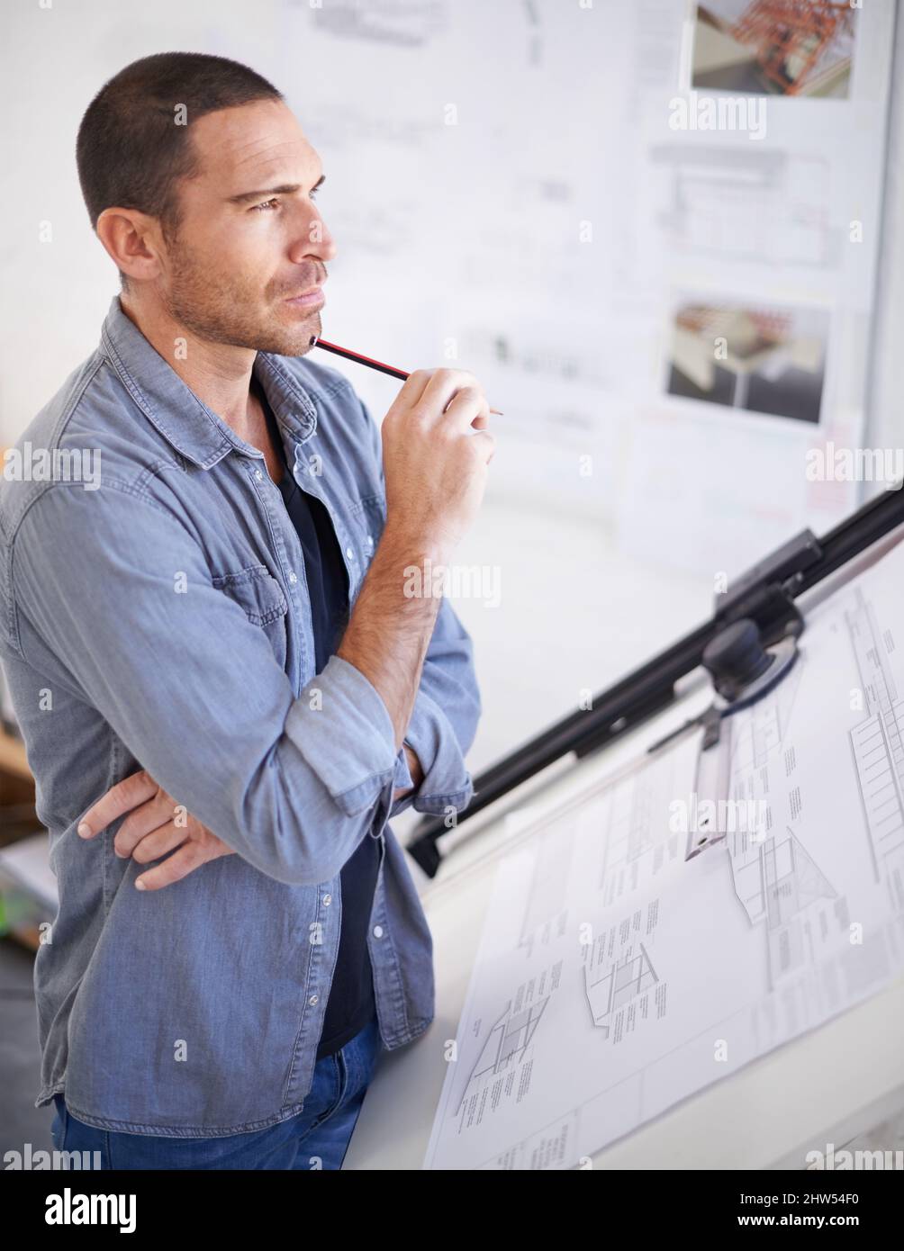 Dar a sus planes un pensamiento profundo antes de hacer cambios. Foto recortada de un arquitecto que parece pensativo al lado de su mesa de dibujo. Foto de stock