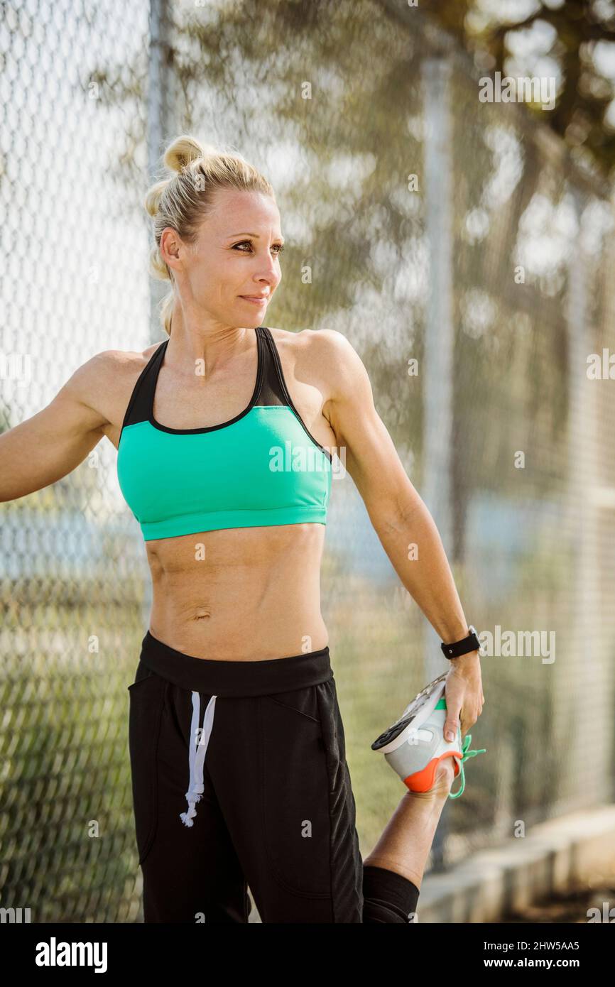 Mujer atleta con ropa deportiva estirada en la valla Foto de stock