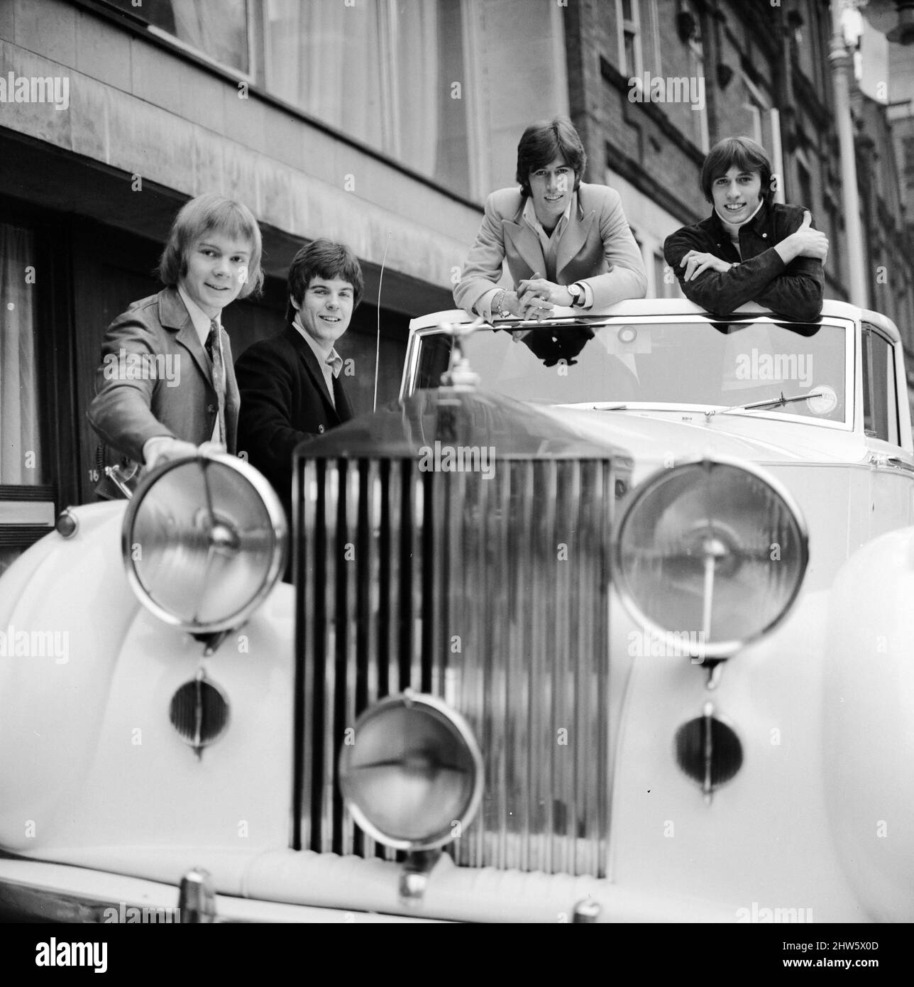 Los Bee Gees examinan un regalo de Navidad temprano del agente Robert Stigwood, un 1948 Rolls Royce Silver Wraith, 12th de diciembre de 1967. El coche fue dado como un regalo especial para marcar y celebrar alcanzar 1 millones de ventas récord de su único Massachusetts. Cuatro de los cinco miembros del grupo miran el coche y lo dan un pulido y limpio. El Sr. Stigwood tenía el coche completamente retapizado y pintado y el motor fue revisado. En la foto: Colin Peterson, Vince Melouney, Barry Gibb y Robin Gibb en Adams Row, Mayfair (Robin Gibb no estaba disponible para la foto) Foto de stock