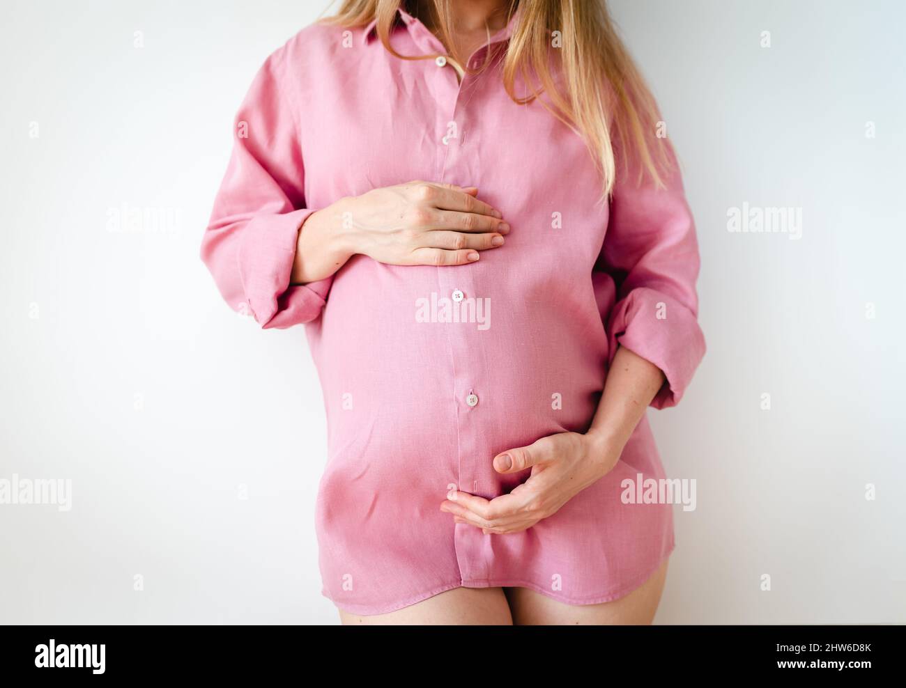 una mujer embarazada está de pie con las manos en su estómago, el concepto de esperar un bebé Foto de stock