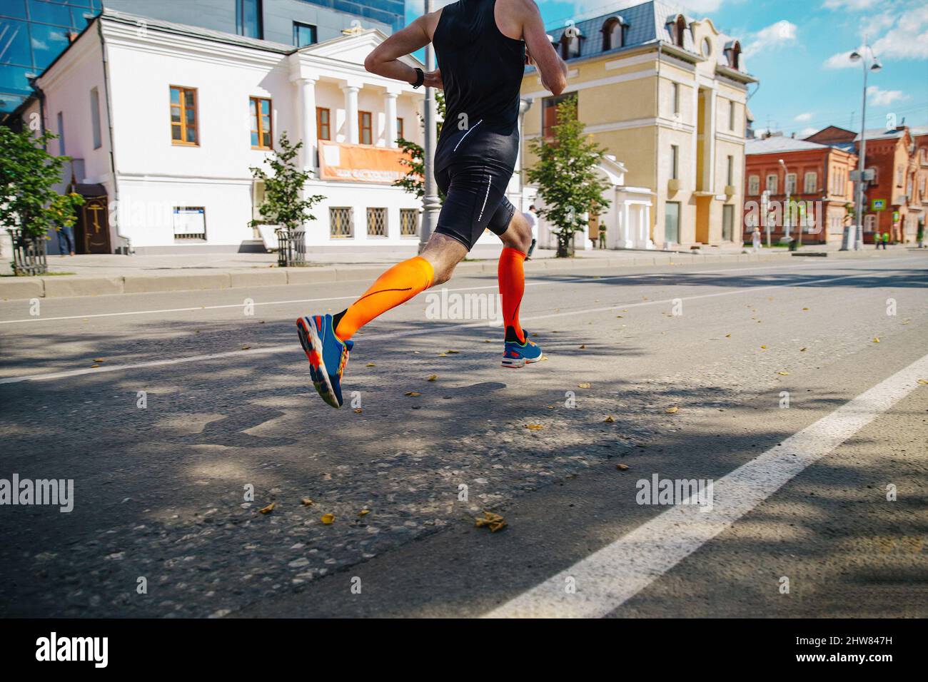 atleta corredor en calcetines de compresión correr maratón en la calle de la ciudad Foto de stock
