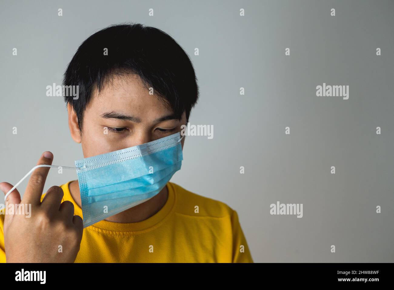 El hombre tuerce las correas de la máscara médica. Este método ayuda a mejorar el ajuste y la filtración de la mascarilla. Protección pandemia mundial de coronavirus. Otros na Foto de stock