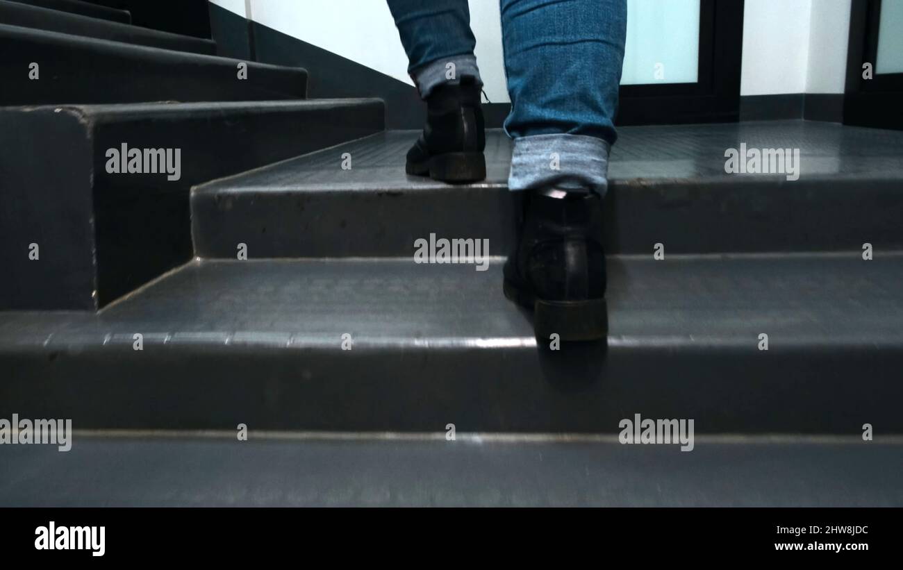 Primer plano de los pies escalando la escalera. Concepto. Hermosos pies en  botas de cuero y jeans subir escaleras en la habitación. La mujer sube  rápidamente las escaleras en el edificio Fotografía