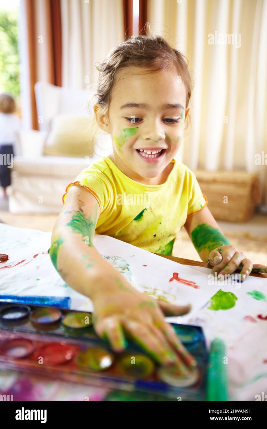 Tienes que hacer un lío para hacer una obra maestra. Tiro de un niño travieso haciendo un lío mientras pintaba. Foto de stock