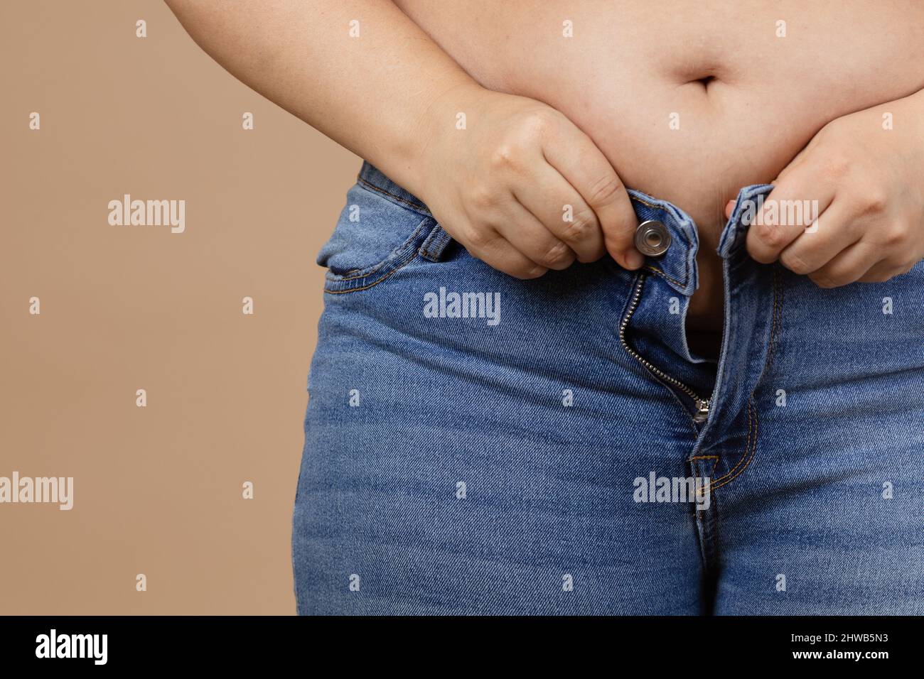 Vientre femenino recortado con sobrepeso y grasa tocando el