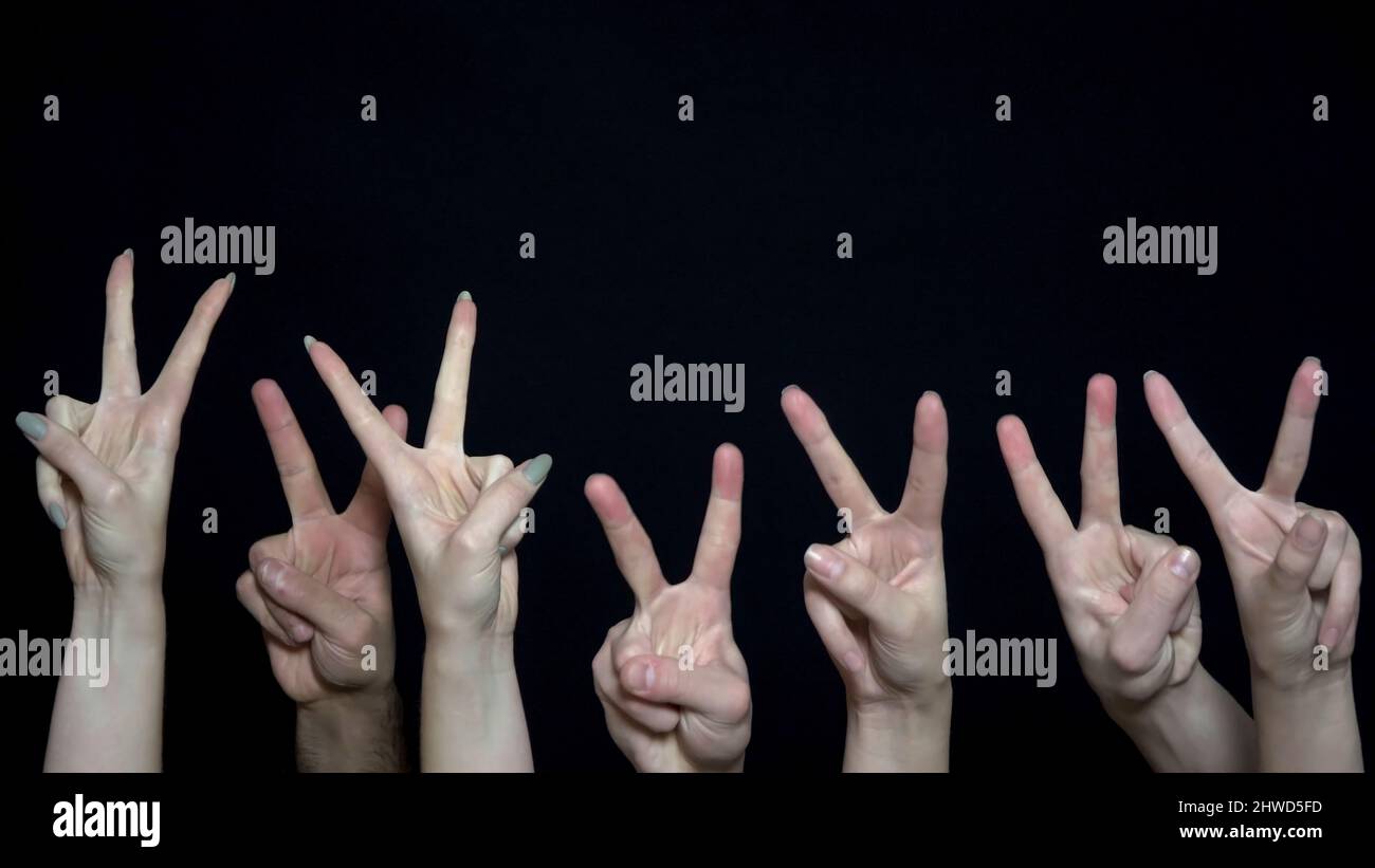 Manos de la muchedumbre con signo de victoria. El primer plano de