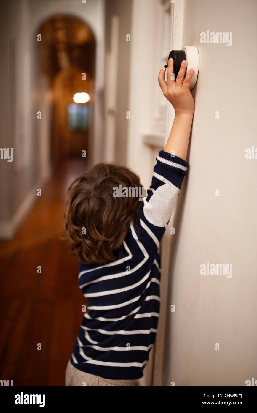 Salvar el planeta de un interruptor a la vez. Una foto recortada de un niño pequeño apagando una luz en su casa. Foto de stock