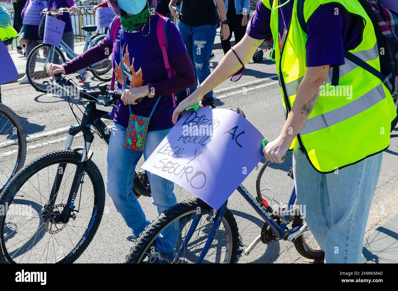 Mujer sosteniendo una bicicleta y una pancarta de papel en una demostración. Traducción: Derecho al aborto legal y seguro. Foto de stock