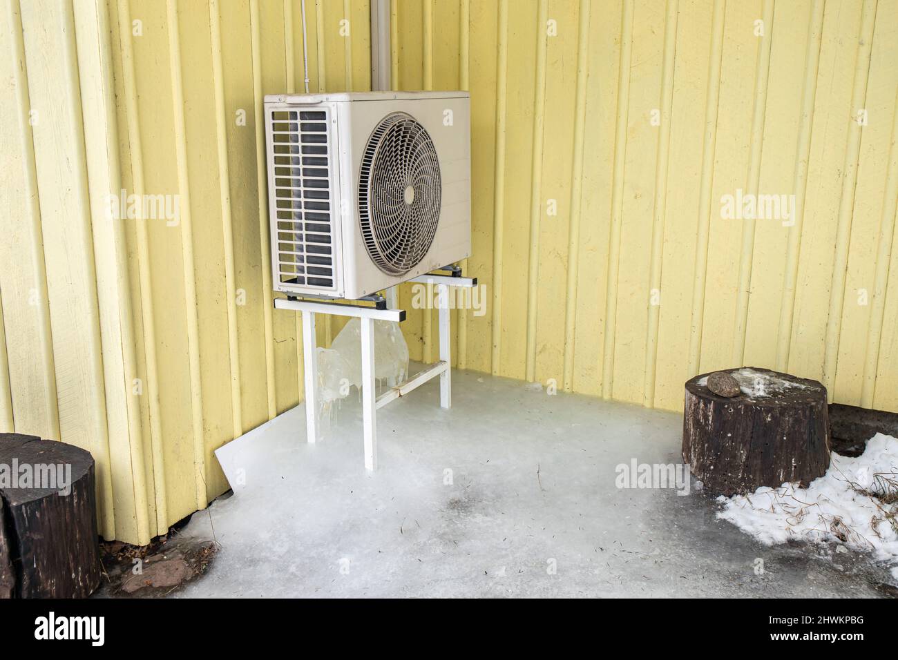 Máquina de aire acondicionado al aire libre en rack en casa doméstica casa  pared amarilla. Mucho hielo bajo él en el frío día de invierno Fotografía  de stock - Alamy