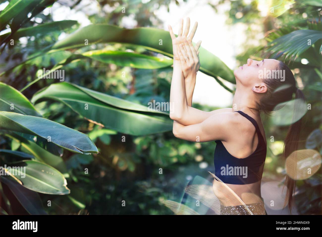 Mujeres meditando y practicando yoga en la selva tropical. Hermosa joven practicando yoga al aire libre con bosque tropical en el fondo. Foto de stock