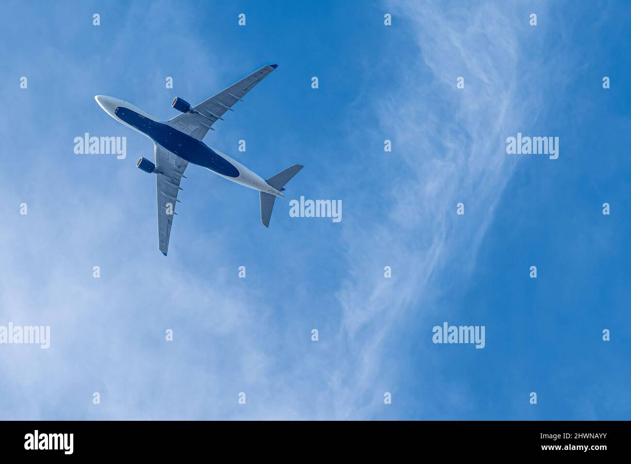 Avión de pasajeros Delta Air Lines volando directamente por encima de un cielo azul con nubes blancas. (EE. UU.) Foto de stock