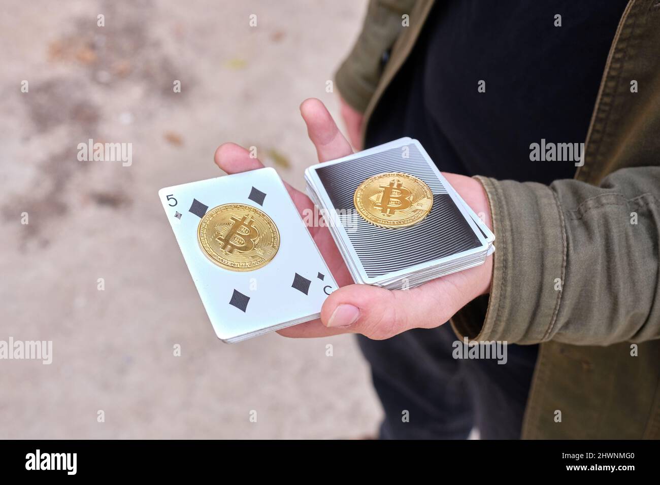 Mago de la calle sosteniendo cartas con una marca de bitcoin en la palma de la mano Foto de stock