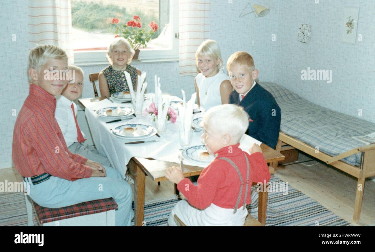 Fotografía original de los años 70 de seis niños suecos sentados en la mesa de comedor, Suecia. Concepto de amistad, unión, antaño, nostalgia Foto de stock