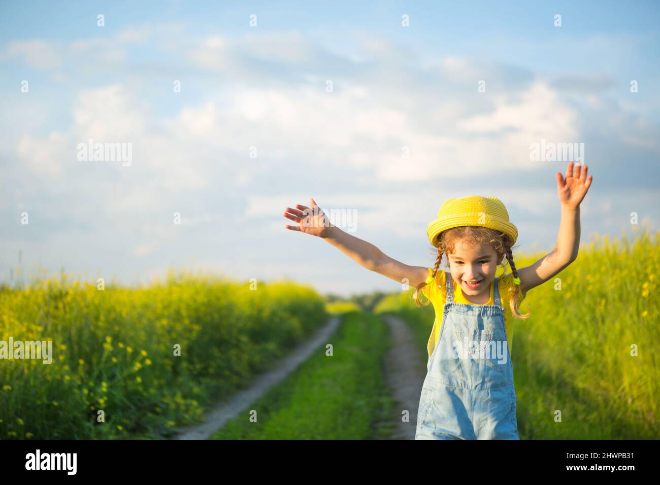 Chica alegre en un sombrero amarillo en un campo de verano ríe y sonríe. Alegría, tiempo soleado, holidays.repelente para mosquitos e insectos. Estilo de vida, amable Foto de stock