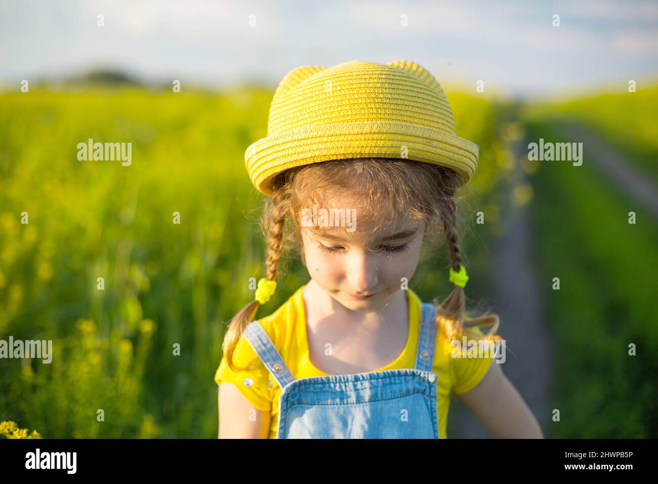 Una chica alegre en un sombrero amarillo en una fela de verano. Día de los niños, alegría, tiempo soleado, vacaciones. Un remedio para mosquitos e insectos. Estilo de vida, tipo f Foto de stock