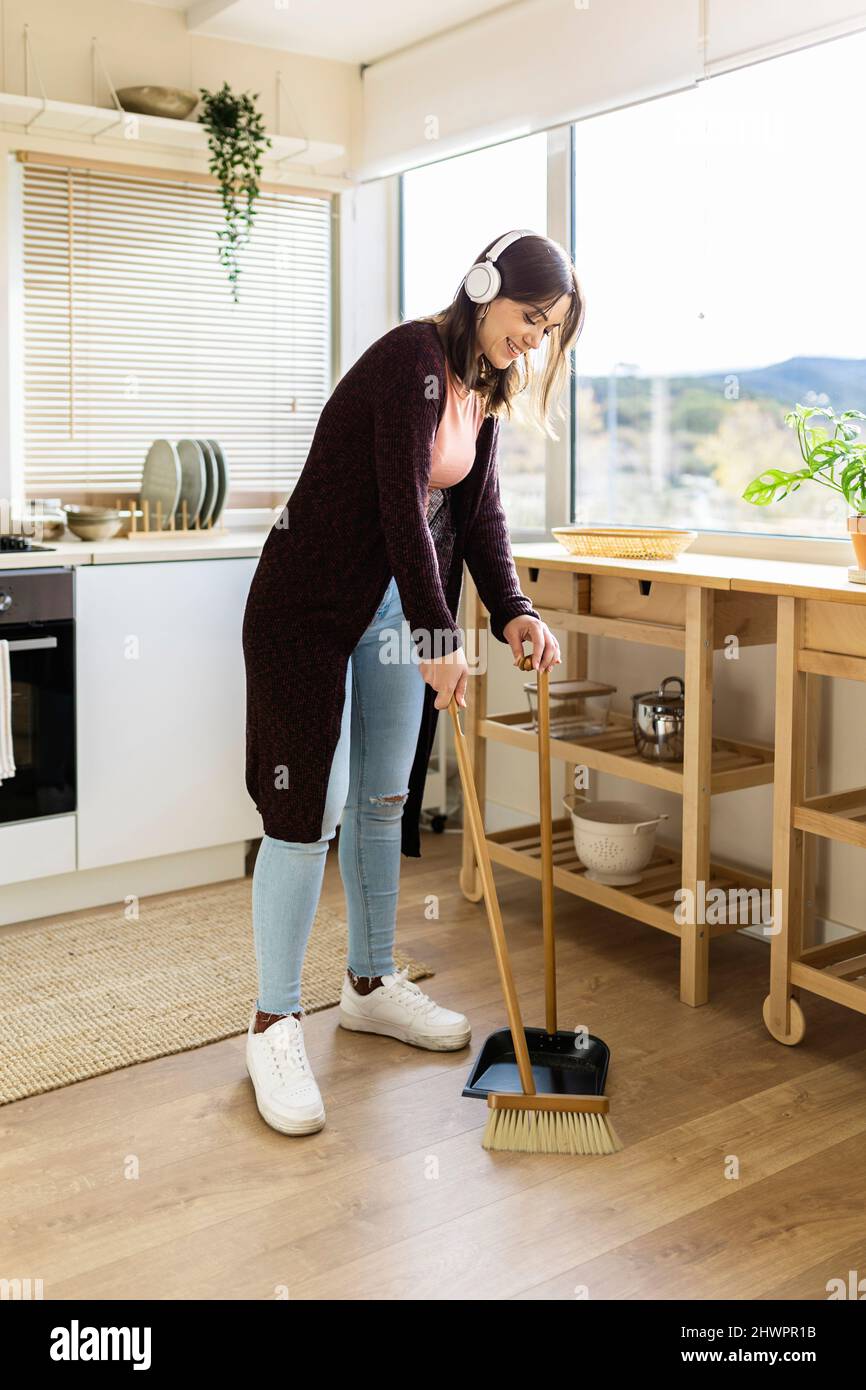 Mujer limpiando el suelo con escoba y recogedor en la cocina de casa  Fotografía de stock - Alamy