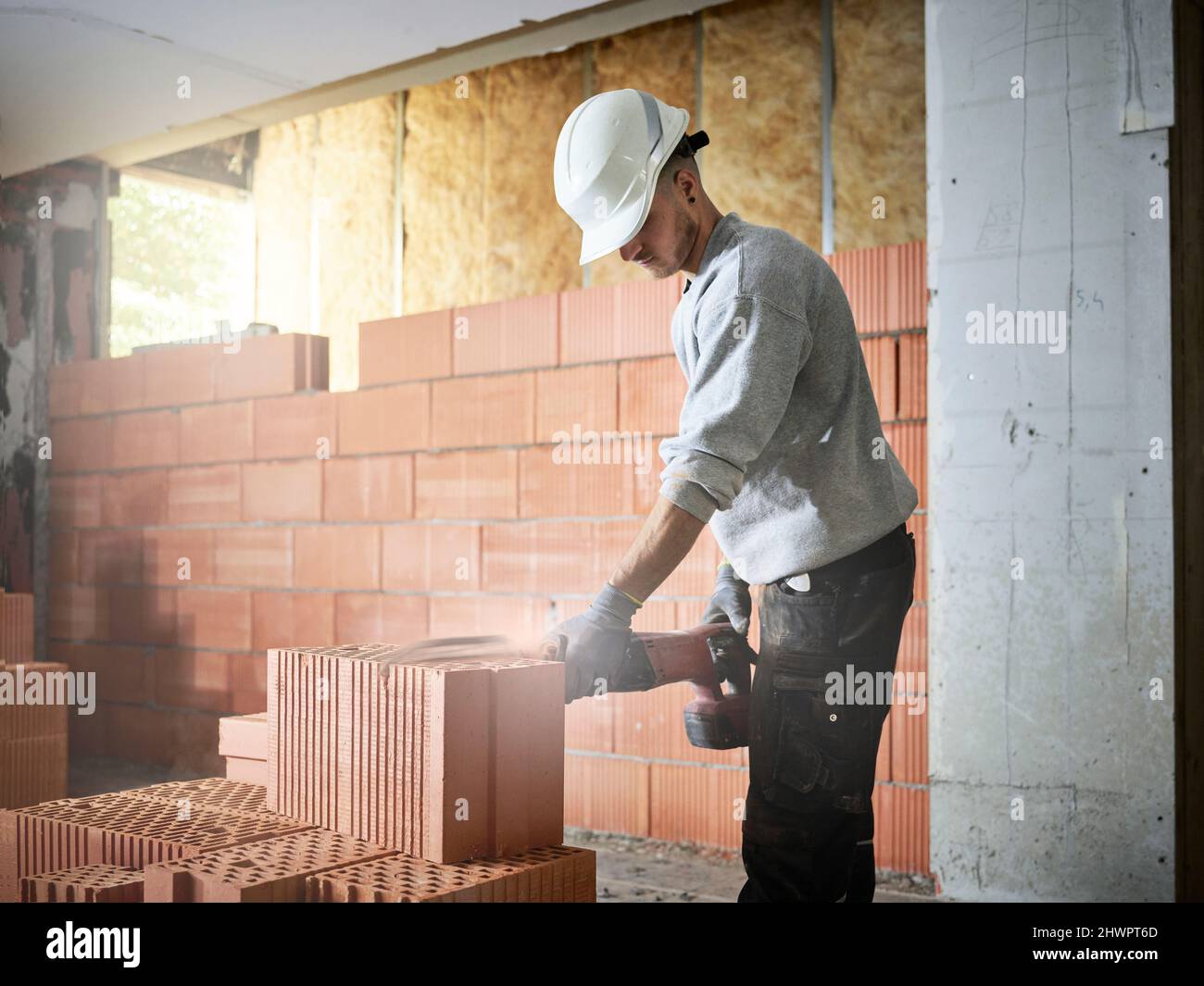 Ladrillo de corte de bricklayer con herramienta de potencia en el lugar de construcción Foto de stock