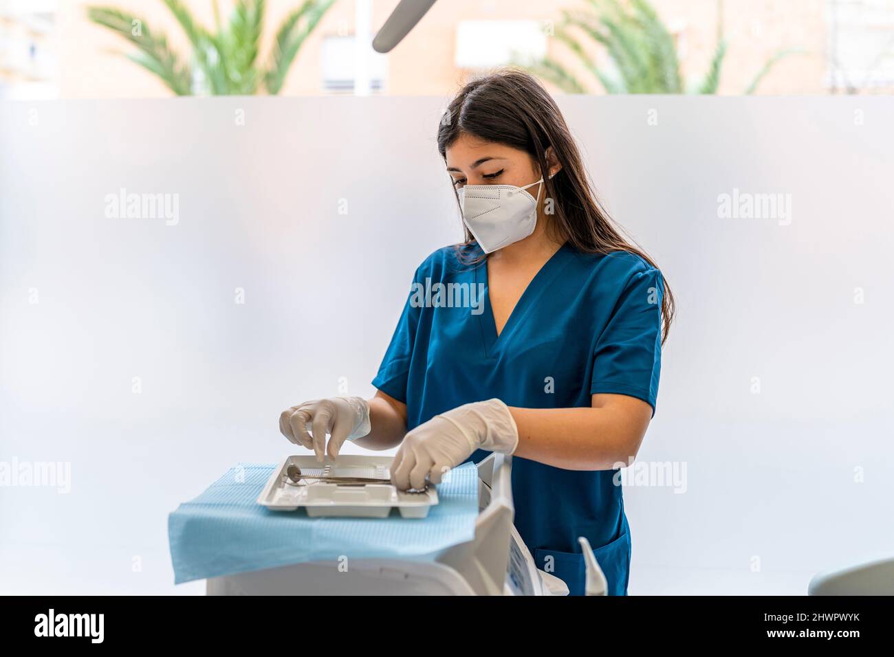 Enfermero que lleva mascarilla protectora arreglando equipo dental en la clínica médica Foto de stock