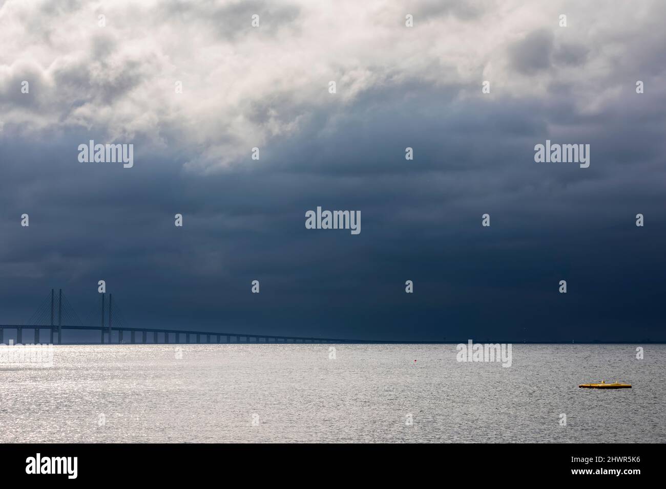 Cielo nublado sobre estrecho de sonido con silueta del puente Oresund en el fondo Foto de stock