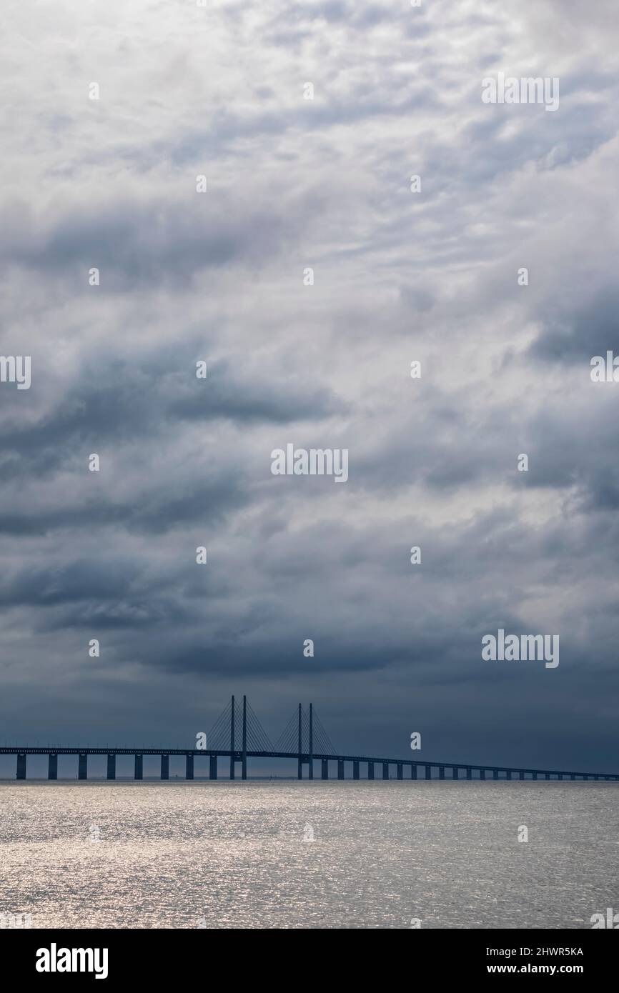 Cielo nublado sobre estrecho de sonido con silueta del puente Oresund en el fondo Foto de stock