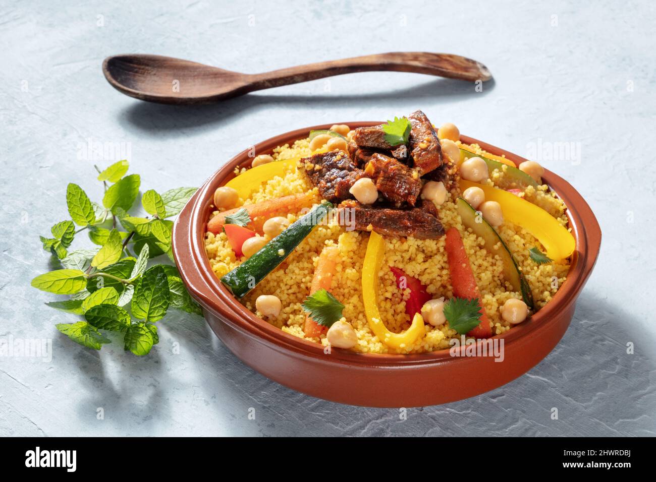 Cuscús de carne y verduras, comida tradicional marroquí, con cilantro fresco y menta. Plato árabe festivo Foto de stock