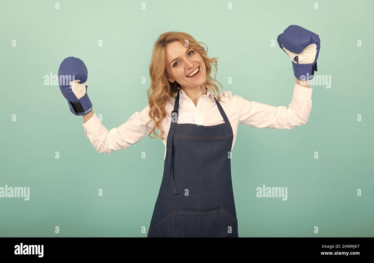 feliz mujer exitosa en delantal de cocina y guantes de boxeo, ama de casa Foto de stock