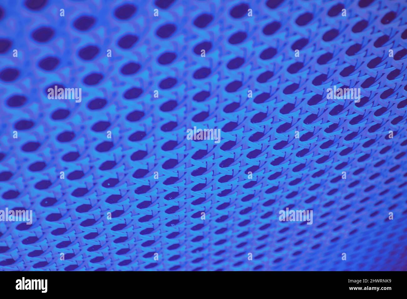 Fondo de pared perforado abstracto resaltado por luces LED de neón azul. Patrones y texturas Foto de stock