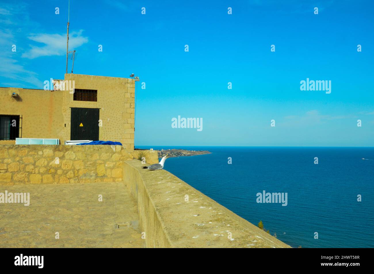 Alicante, España - Julio 17 2019: Vista desde el Castillo de Santa Bárbara hasta el Mar Mediterráneo frente a Alicante. En la pared del castillo se encuentra un seagu Foto de stock