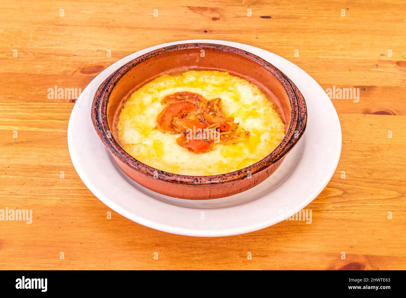 Gran receta italiana para una porción de queso provolone a la parrilla en  una olla de barro con tomate y pimiento picado en el centro de la comida  Fotografía de stock -