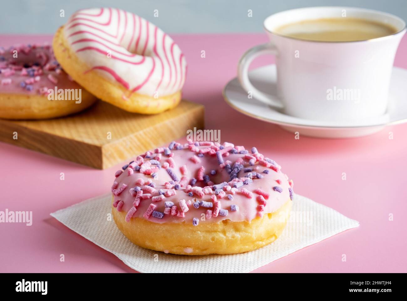 Tres deliciosos donuts recién glaseados y una taza de café caliente fresco Foto de stock