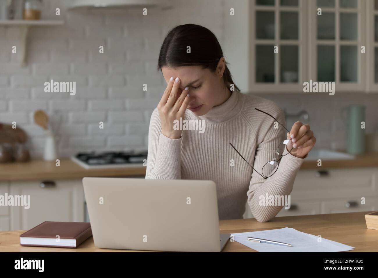 Una mujer cansada se quita las gafas del trabajo con el portátil Foto de stock