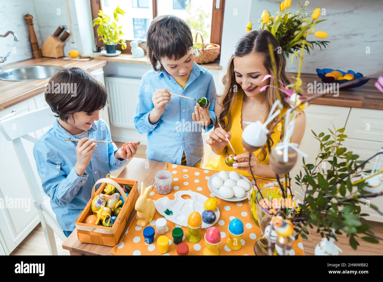 Madre e hijos coloreando huevos para Pascua Foto de stock