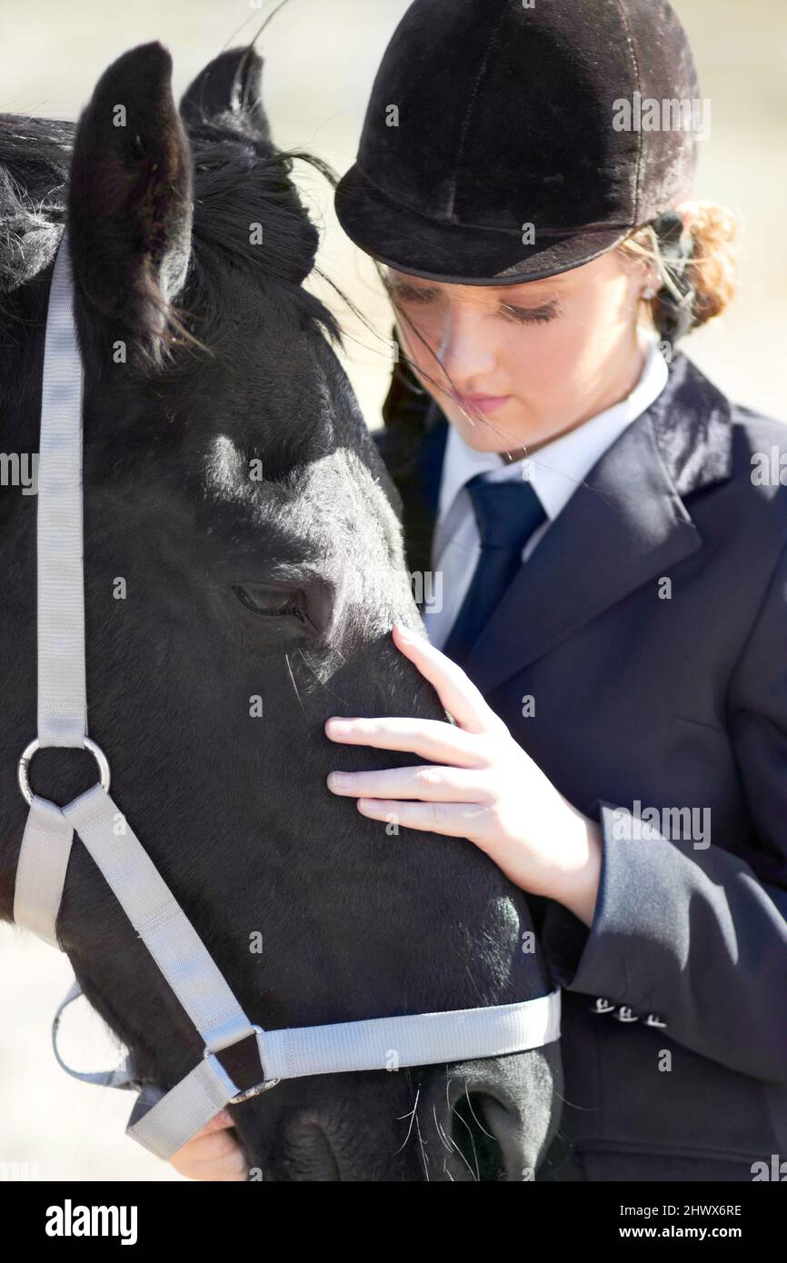 Es más que un animal para mí. Tiro de una hermosa joven de pie junto a su caballo. Foto de stock