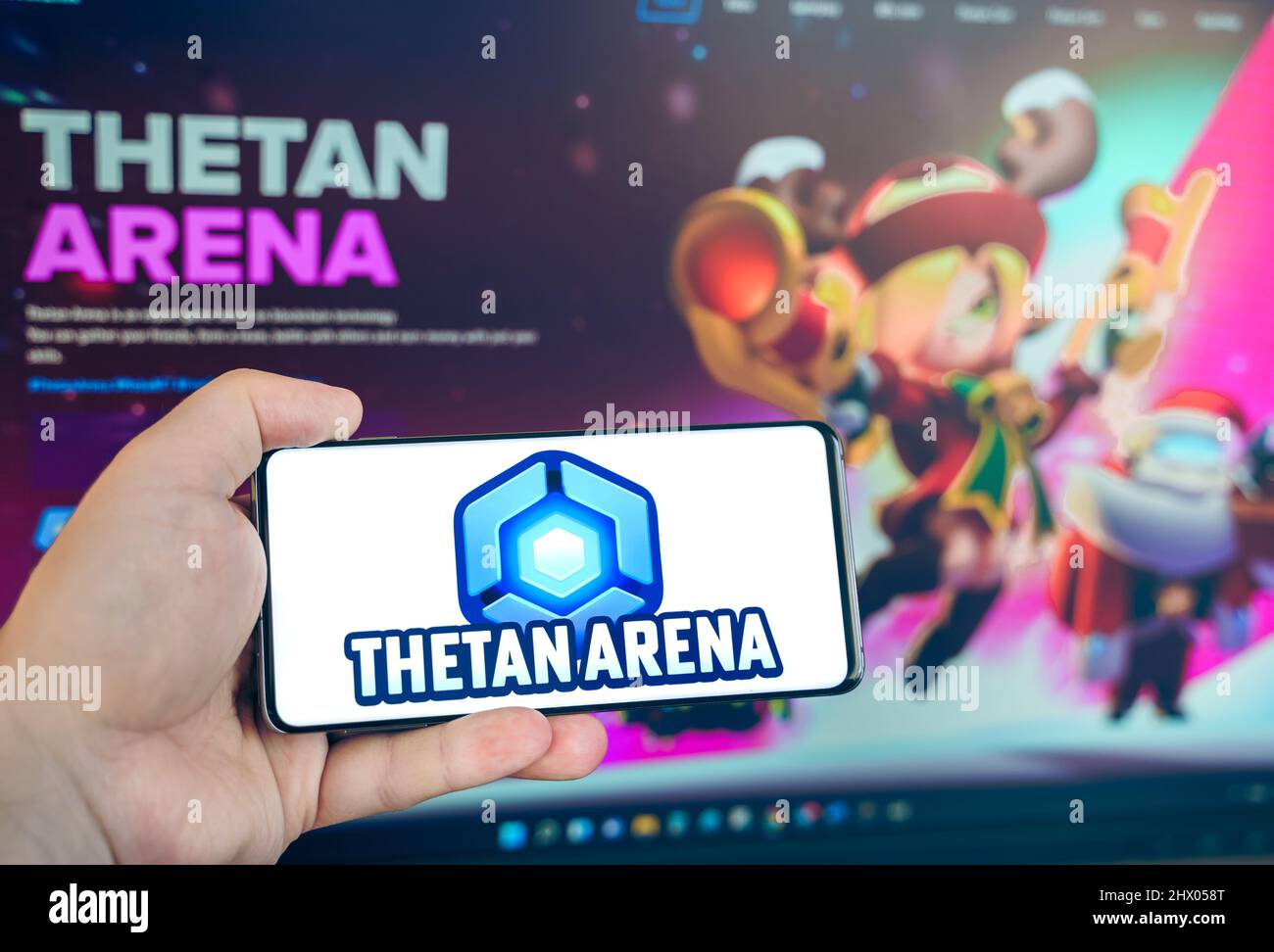 Rusia Moscú 25.12.2021 Logotipo de Thetan Arena. Blockchain nft ethereum juego de estrategia de criptomoneda. Hombre jugando en el teléfono móvil. Moneda de Crypto, token. E Foto de stock