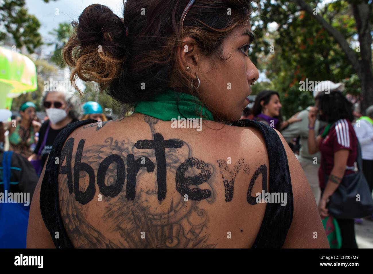 Caracas, Venezuela. 08th Mar, 2022. Una mujer con una bufanda verde alrededor de su cuello y un eslogan para la despenalización del aborto en su espalda toma parte en un mitin para conmemorar el Día Internacional de la Mujer. Crédito: Boris Vergara/dpa/Alamy Live News Foto de stock