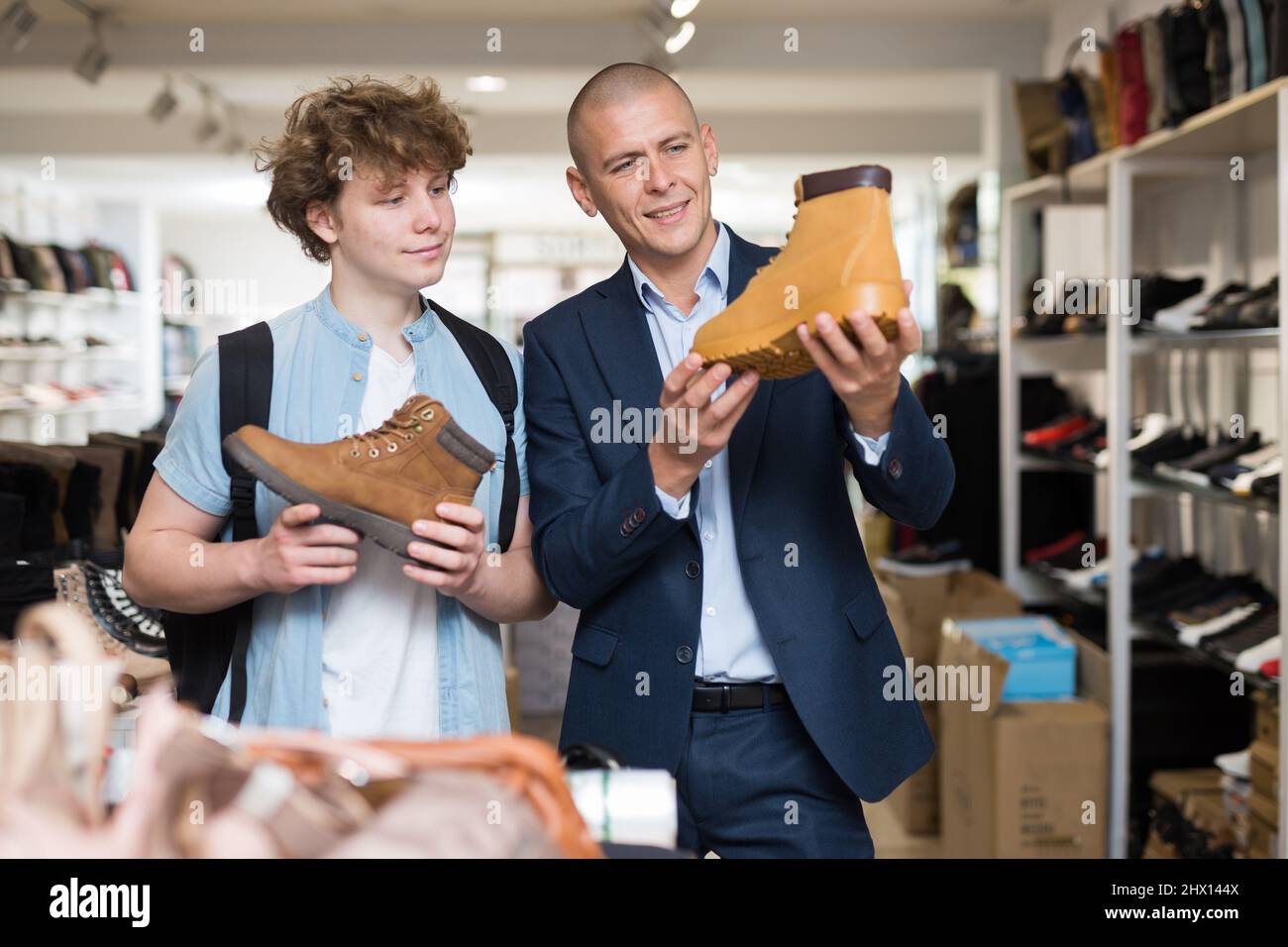 Hombre y adolescente en busca de zapatos para hombre de temporada demi en la tienda Foto de stock