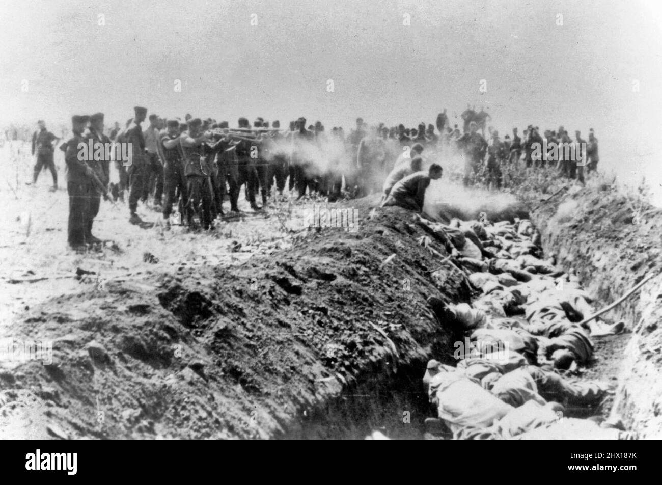 Hombres con una unidad no identificada ejecutan a un grupo de civiles soviéticos arrodillados al lado de una fosa común durante la Segunda Guerra Mundial Foto de stock