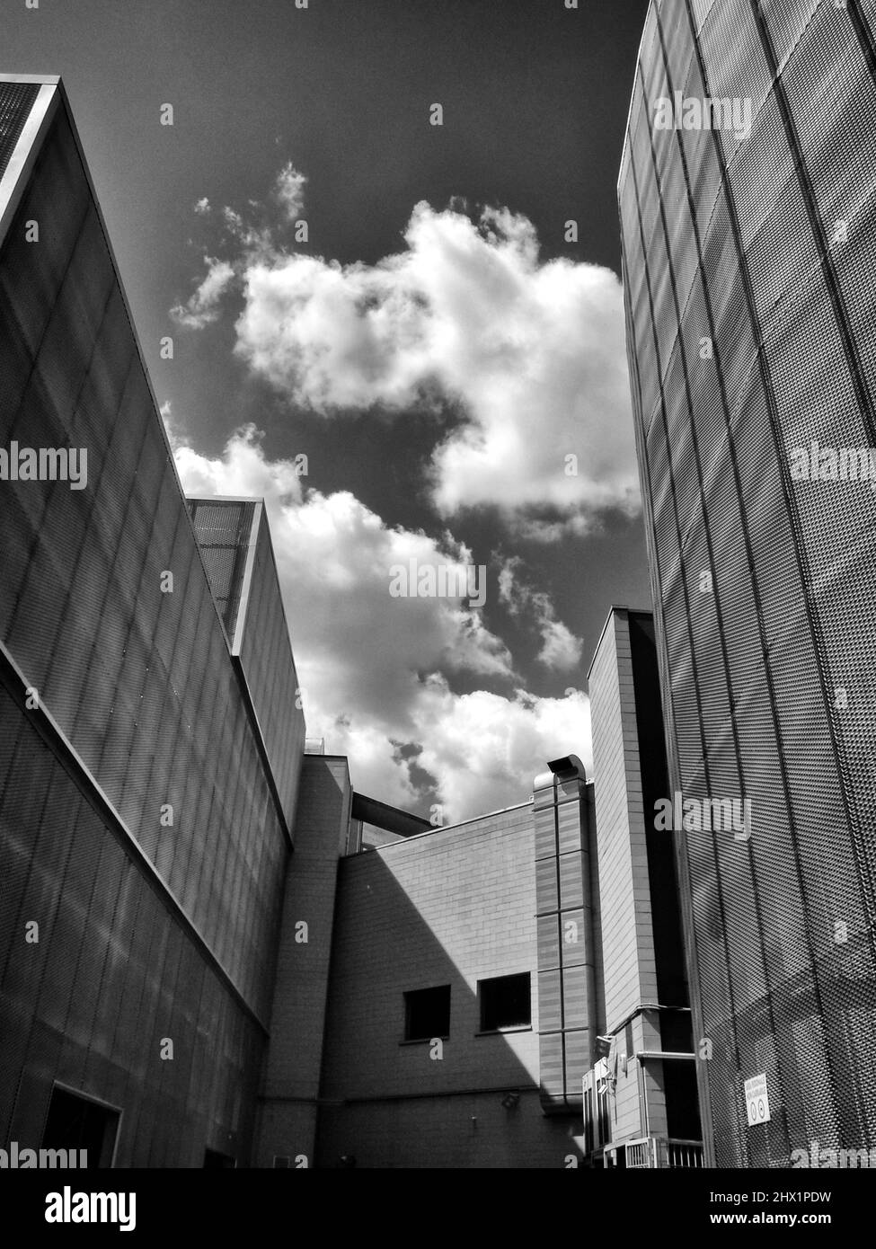 Edificio de arquitectura moderna con nubes blancas en el cielo - fotografía monocromática de arte fino Foto de stock