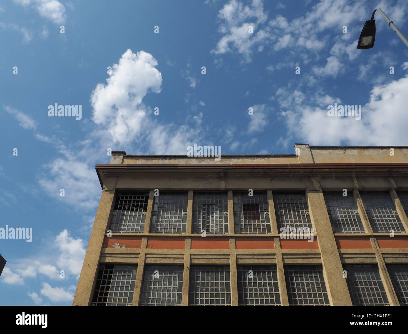 Fotografía artística de un antiguo edificio industrial con nubes blancas en el cielo azul Foto de stock