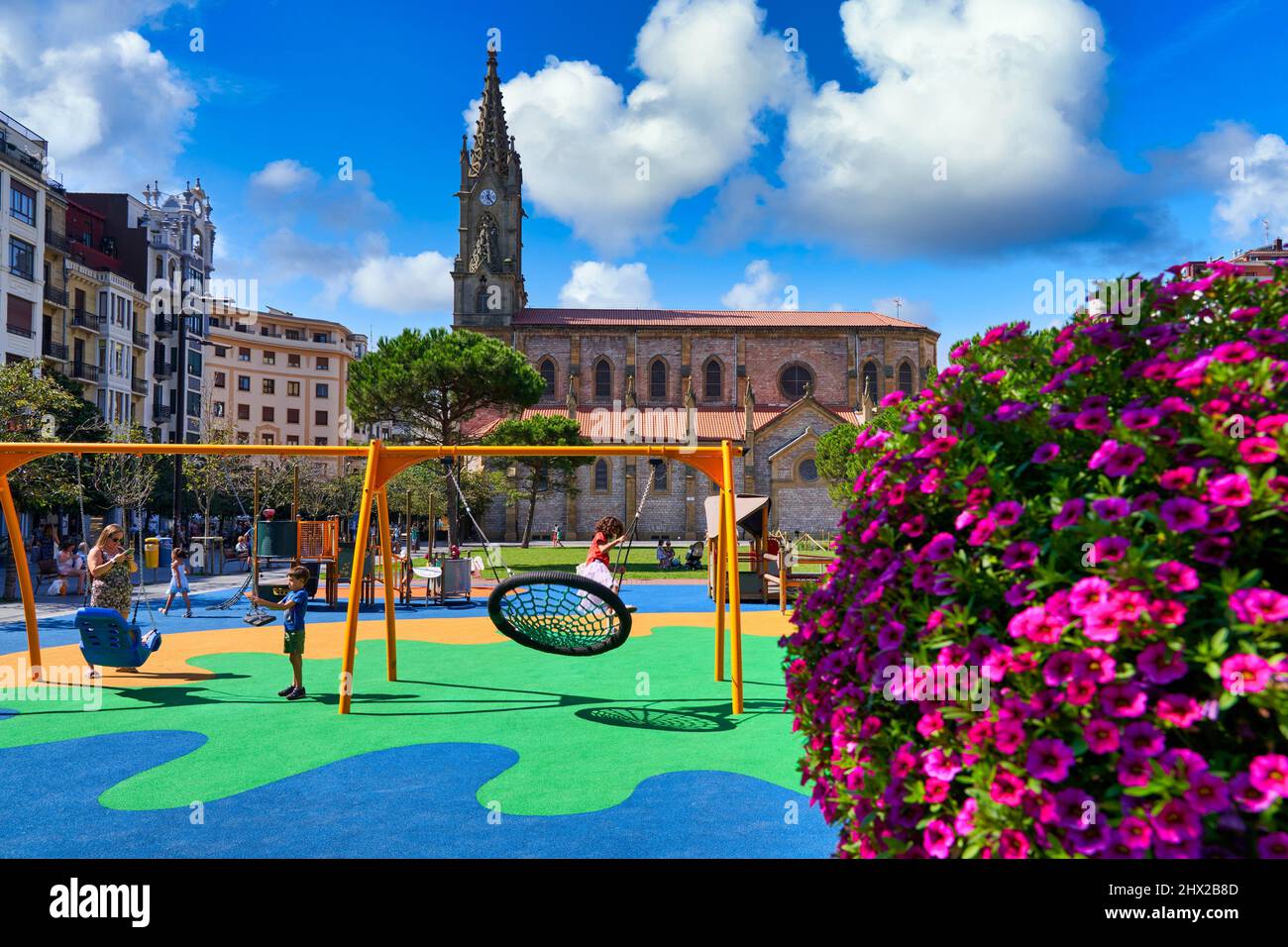 Niños jugando en un patio de recreo, Plaza Cataluña y parroquia de San