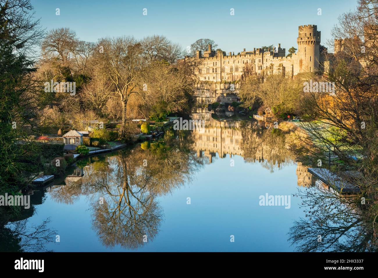 17 de enero de 2022: Castillo de Warwick, Warwickshire, Reino Unido - Castillo de Warwick reflejado en el río Avon en un hermoso día soleado de invierno con cielo azul claro. Foto de stock