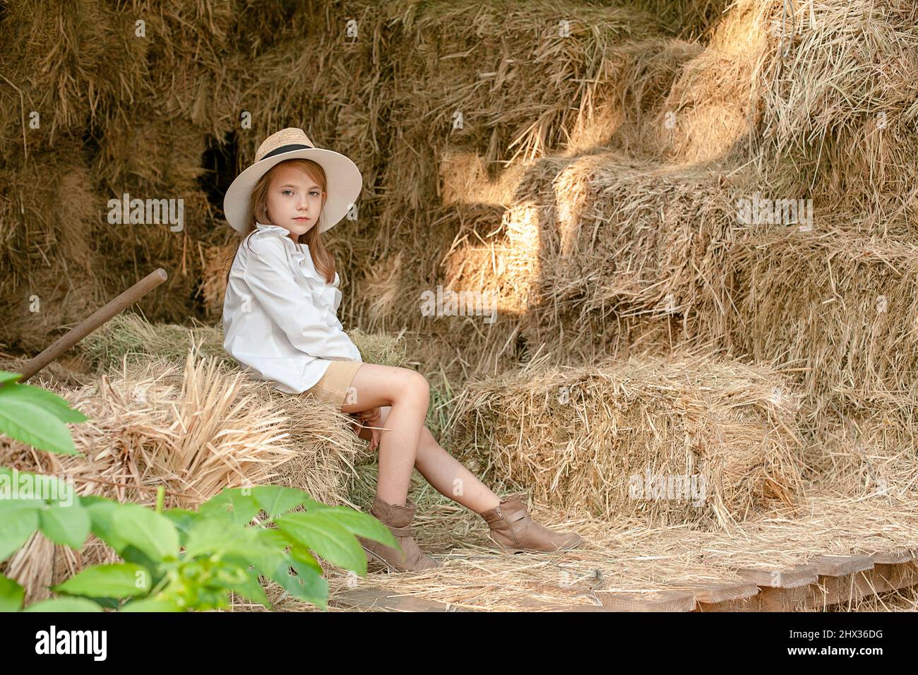 Niña pequeña con ropa de estilo campestre sentada en el haystack en hayloft  Fotografía de stock - Alamy