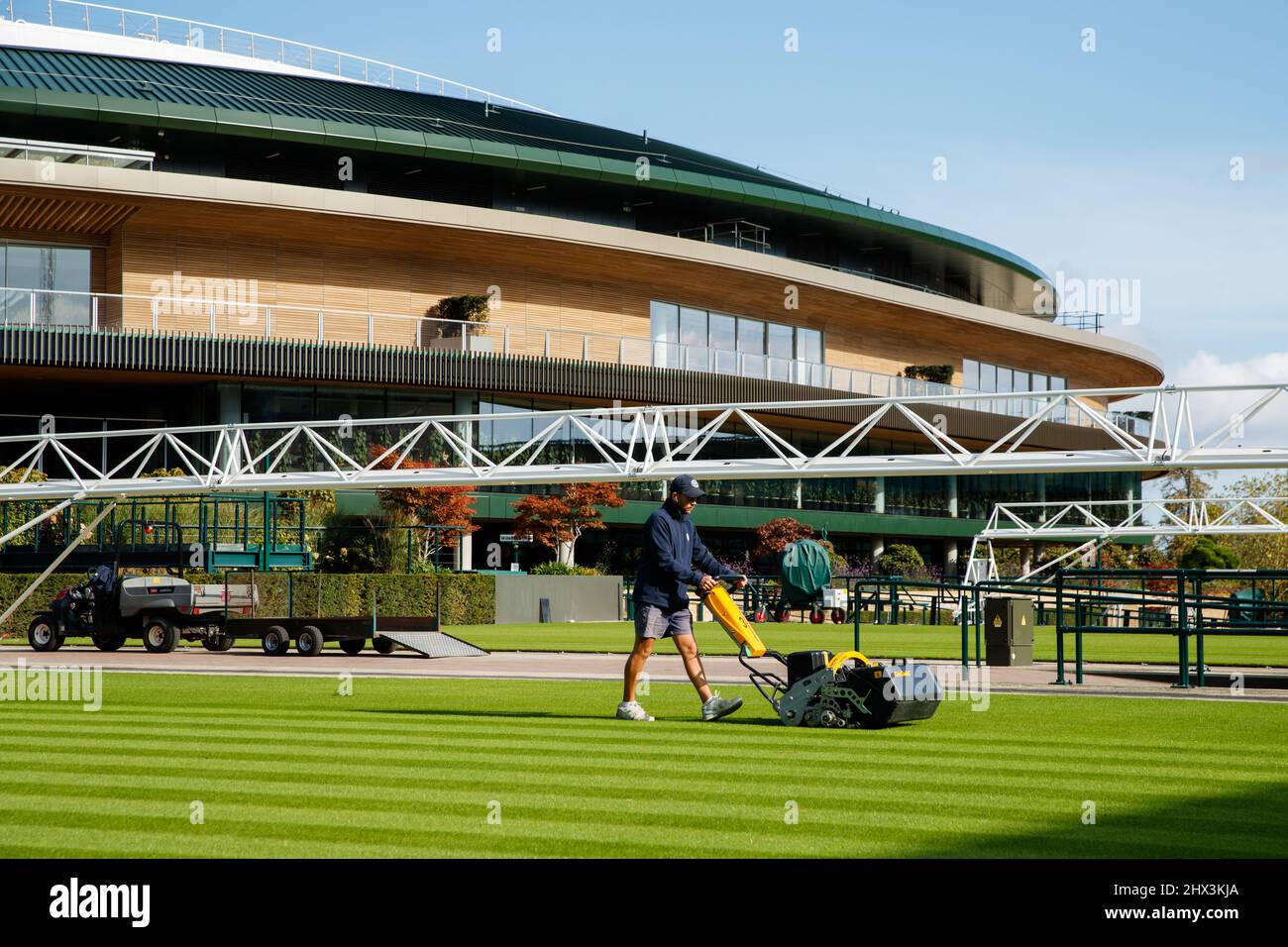 Groundman corta el césped frente a la Corte No.1 en el All England Lawn Tennis Club, sede de los Campeonatos de Wimbledon Foto de stock