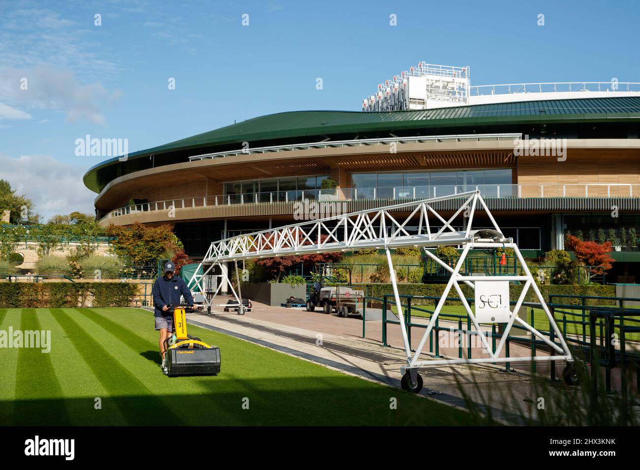 Groundman corta el césped frente a la Corte No.1 en el All England Lawn Tennis Club, sede de los Campeonatos de Wimbledon Foto de stock