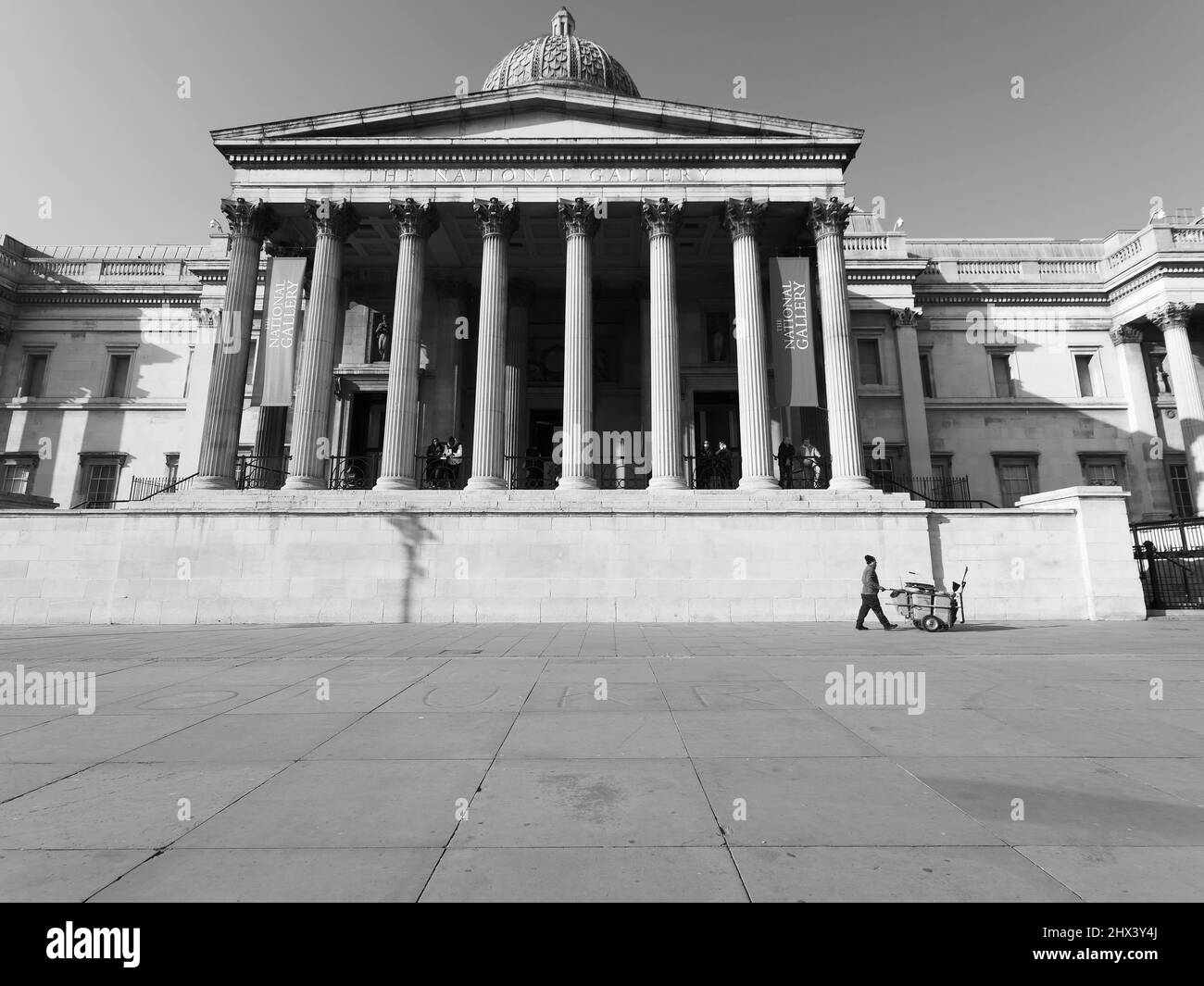 Londres, Gran Londres, Inglaterra Marzo 08 2022: El Recolector de Rechazar pasa frente a la Galería Nacional en Trafalgar Square. Monocromo. Foto de stock