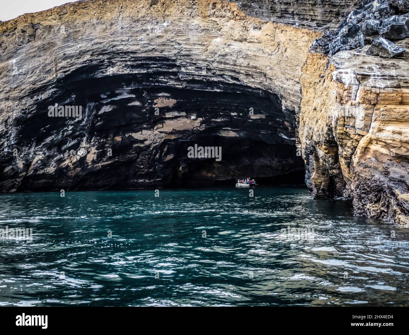 Los turistas en un zodiaco de caucho inflable entran en una cueva en Isala Isabela, Galápagos, Ecuador Foto de stock