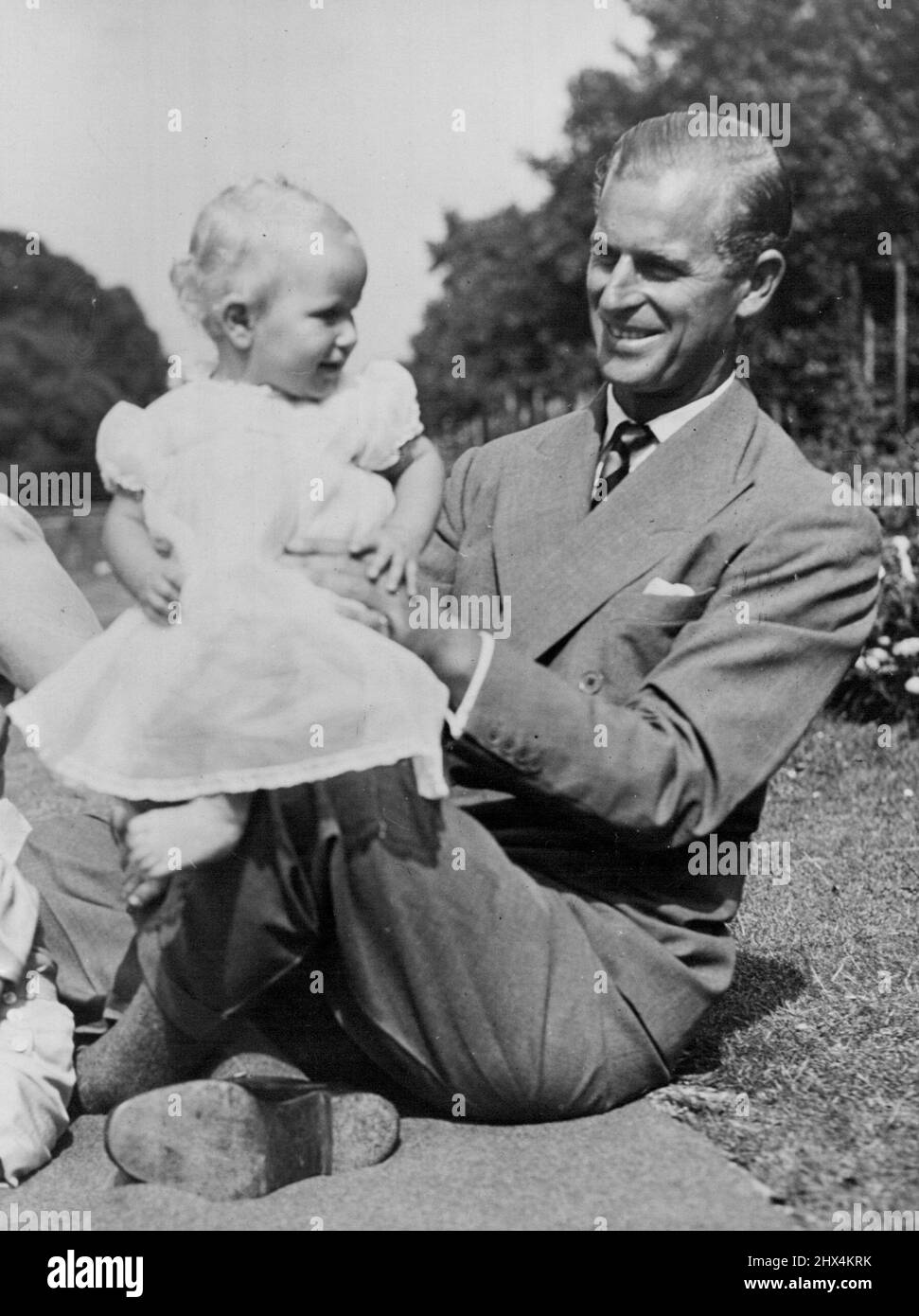 Una familia feliz en su jardín -- la princesa Anne rebota felizmente en la  rodilla de su padre. Imagen recién estrenada del espectáculo .  Princess Elizabeth y el Duque de Edimburgo con